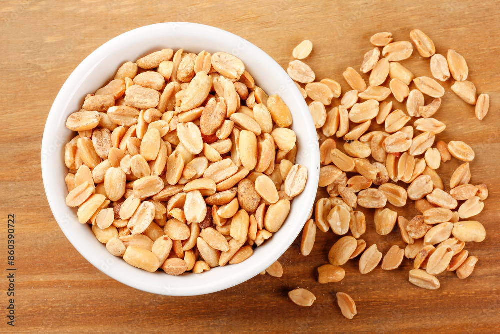Roasted peeled peanuts in bowl on wooden table Roasted peeled peanuts in bowl on wooden table