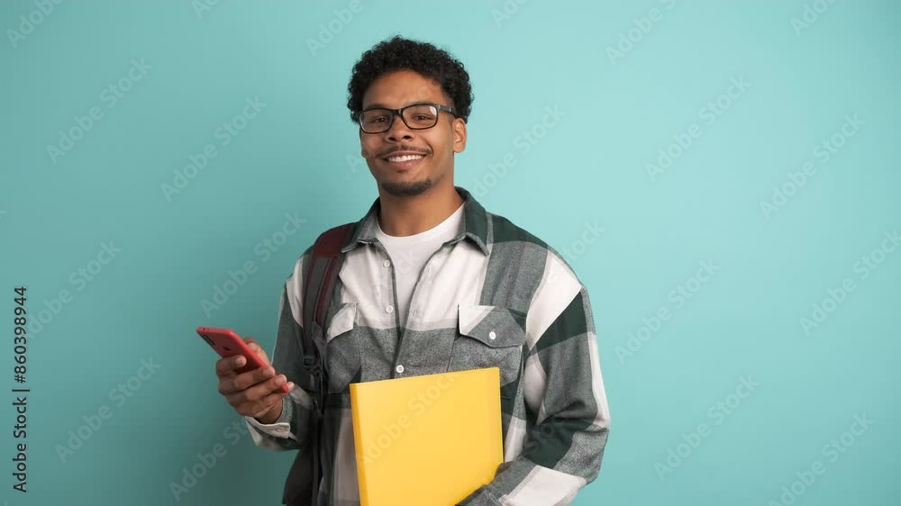 Confident male university student using smartphone in blue studio Confident male university student using smartphone in blue studio
