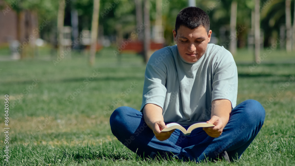 Young man reading a book sitting on the grass Young man reading a book sitting on the grass