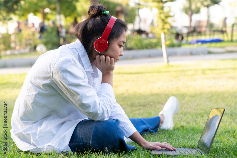 Fototapeta premium Young beautiful Asian woman working with laptop/internet/online shopping at outdoor park,