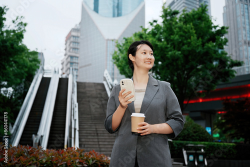 Businesswoman in City Holding Coffee and Phone