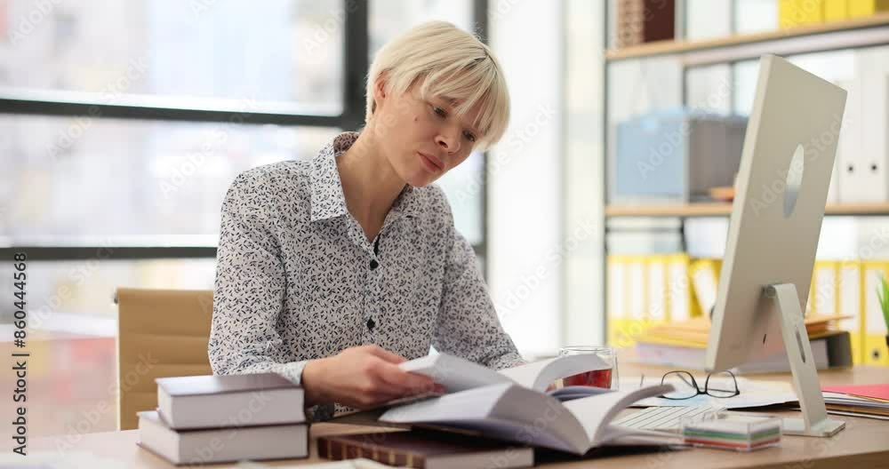 Thoughtful woman turns pages of planner at computer in company office. Business lady checkups schedule of actual work tasks at desk Thoughtful woman turns pages of planner at computer in company office. Business lady checkups schedule of actual work tasks at desk