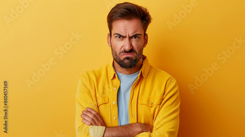  Angry man with crossed arms in front of yellow background. Copy space. Generative AI  © Volodymyr
