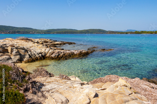 Beautiful rocky Aegean Sea coast with shallow turquoise blue water at a Vourvourou Beach, Sithonia, Chalkidiki peninsula, Central Macedonia, Northern Greece photo