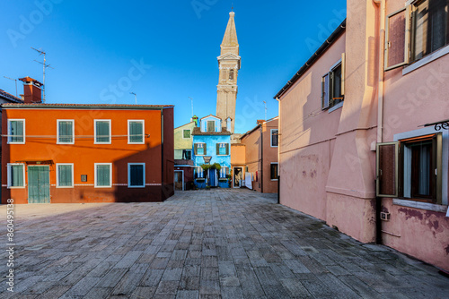 Bunte Häuser auf der Insel Burano mit Kirche zum Heiligen Martin Vescovo und dem schiefen Glockenturm im Hintergrund photo