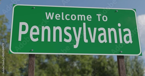Driving By A Welcome To Pennsylvania Green Road Sign Against a Blue Sky and Clouds.
