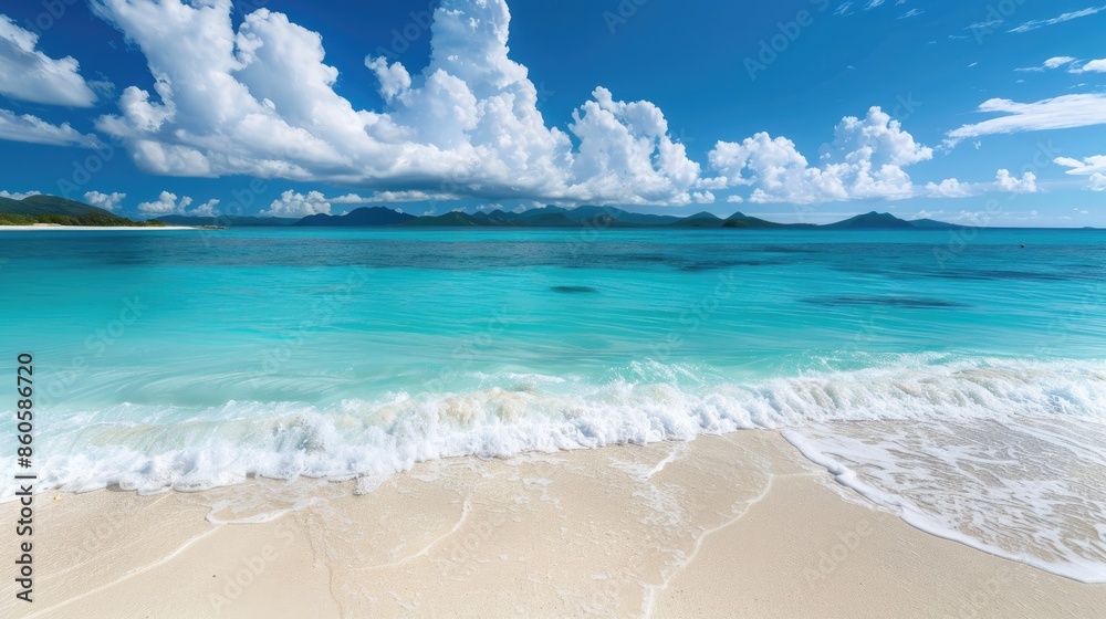 Obraz premium Soft white sand meeting turquoise water under a clear blue sky with fluffy white clouds