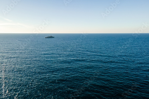 Aerial top view by drone of the sea with warship on horizon.