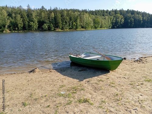 Old green boat standing on the shore of  lake on clear day,
