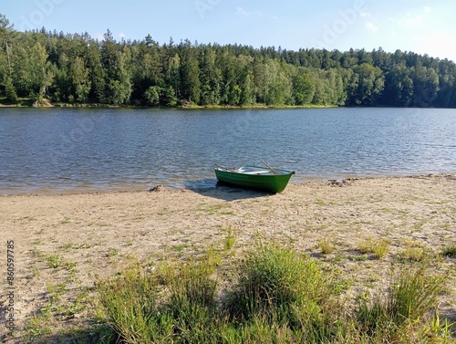 Old green boat standing on the shore of  lake on clear day,