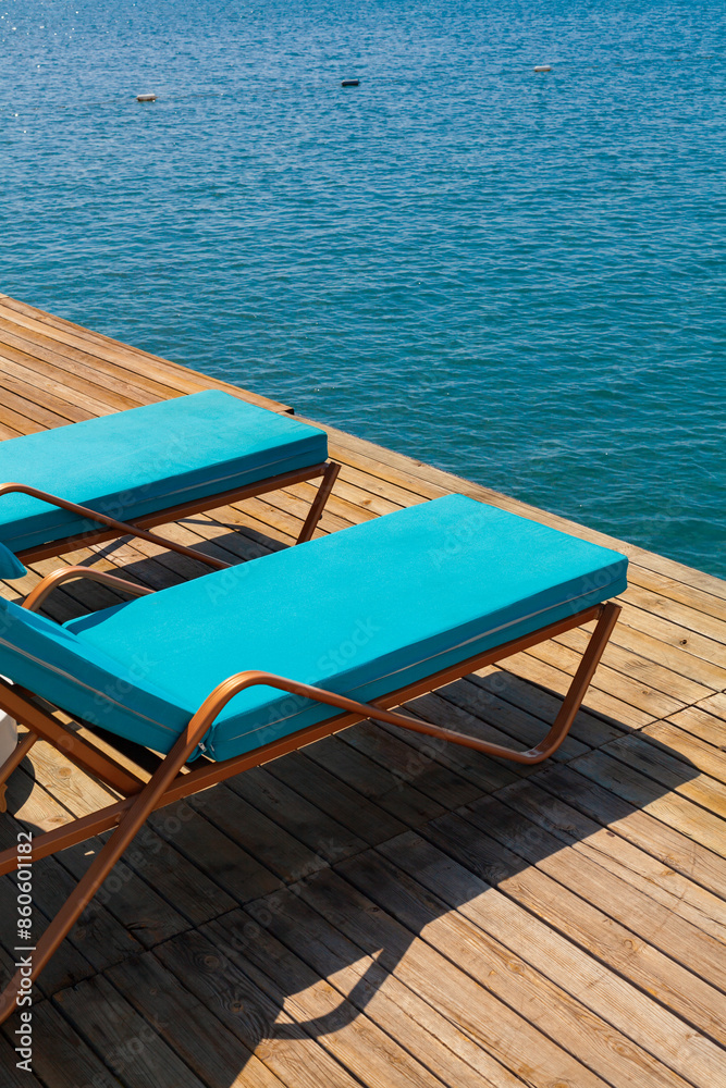 Group of luxury sun beds on a wooden jetty waiting for tourists in a hot summer day. Group of luxury sun beds on a wooden jetty waiting for tourists in a hot summer day.