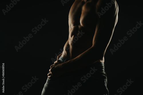 Silhouette of a muscular man with defined abs shot in dark moody lighting, emphasizing fitness and strength. Ideal for fitness, health, and wellness concepts.