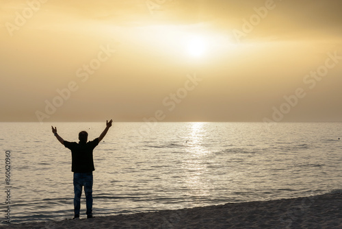 siluette con sfondo il mare e il cielo al tramonto con dominante giallo