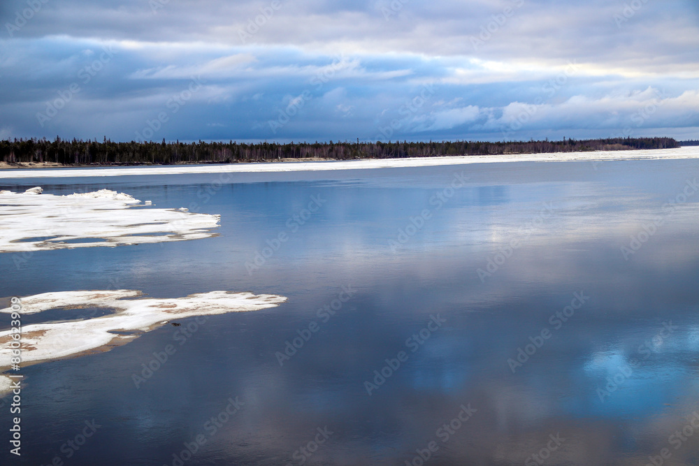 Spring flood, river with remnants of ice, melting ice, landscape river ice spring, thawed dangerous ice.