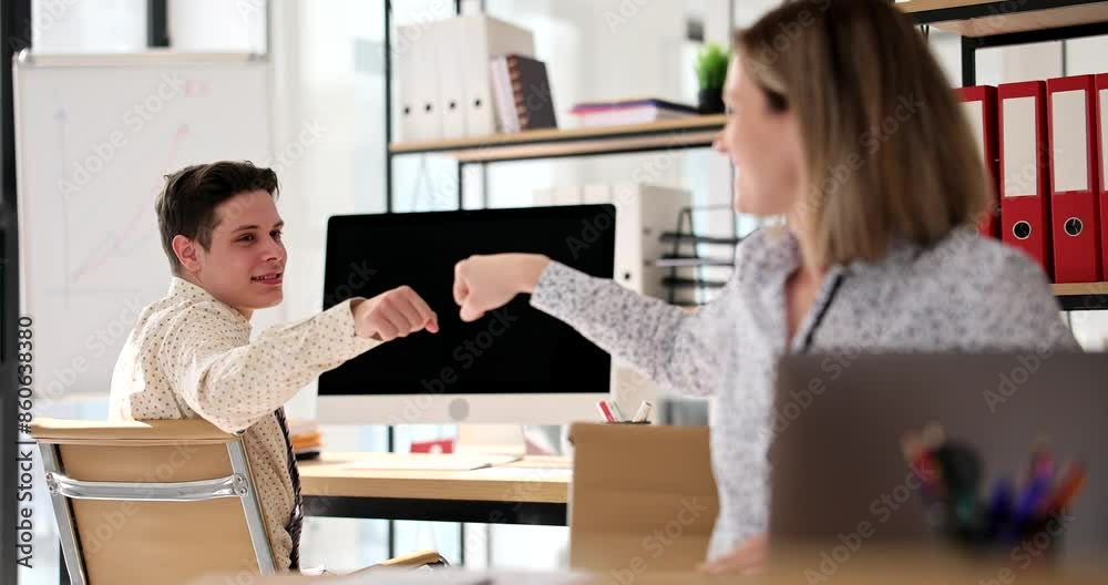 Positive colleagues bumps fists celebrating successful deal in office slow motion. Man and woman employees show support at workplace