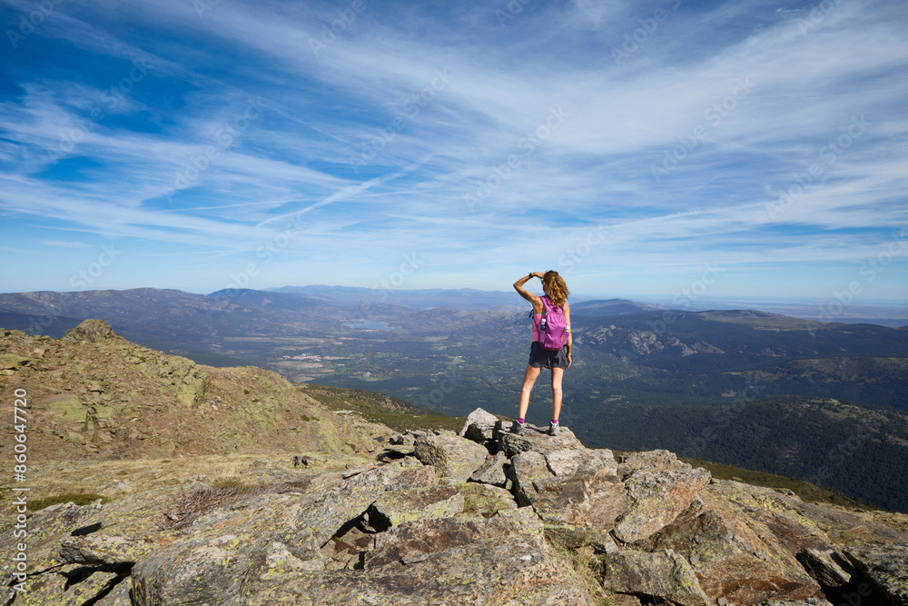 Mountaineer trekking woman with on the top of Peñalara peak, the highest mountain in Madrid, looking towards the horizon. In the Guadarrama National Park, Spain Mountaineer trekking woman with on the top of Peñalara peak, the highest mountain in Madrid, looking towards the horizon. In the Guadarrama National Park, Spain