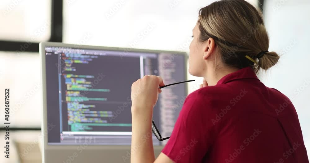 Female programmer with glasses in hand checkups code working on computer in office. Software developer sits at workplace slow motion Female programmer with glasses in hand checkups code working on computer in office. Software developer sits at workplace slow motion
