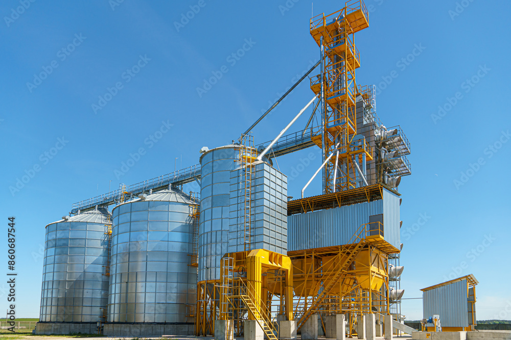 silver silos on agro manufacturing plant for processing drying cleaning and storage of agricultural products, flour, cereals and grain. Large iron barrels of grain. Granary elevator silver silos on agro manufacturing plant for processing drying cleaning and storage of agricultural products, flour, cereals and grain. Large iron barrels of grain. Granary elevator