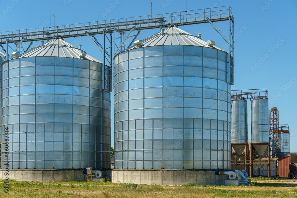 silver silos on agro manufacturing plant for processing drying cleaning and storage of agricultural products, flour, cereals and grain. Large iron barrels of grain. Granary elevator silver silos on agro manufacturing plant for processing drying cleaning and storage of agricultural products, flour, cereals and grain. Large iron barrels of grain. Granary elevator