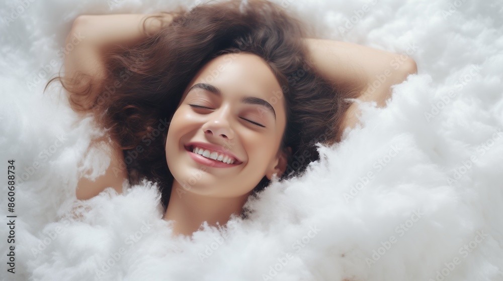 Joyful woman lying on a fluffy white surface with a bright smile Joyful woman lying on a fluffy white surface with a bright smile