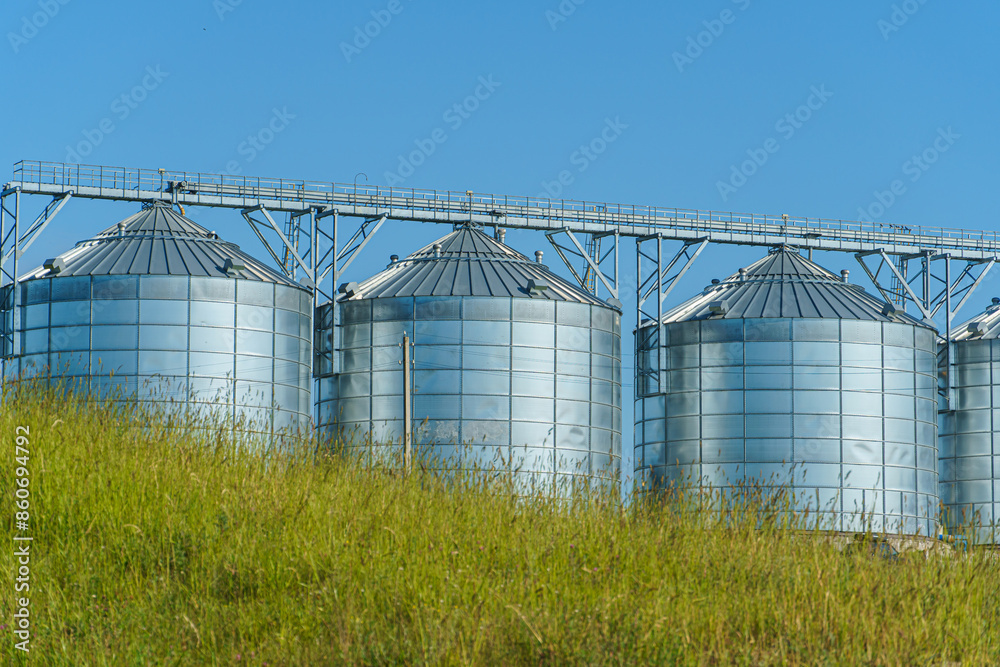 silver silos on agro manufacturing plant for processing drying cleaning and storage of agricultural products, flour, cereals and grain. Large iron barrels of grain. Granary elevator silver silos on agro manufacturing plant for processing drying cleaning and storage of agricultural products, flour, cereals and grain. Large iron barrels of grain. Granary elevator