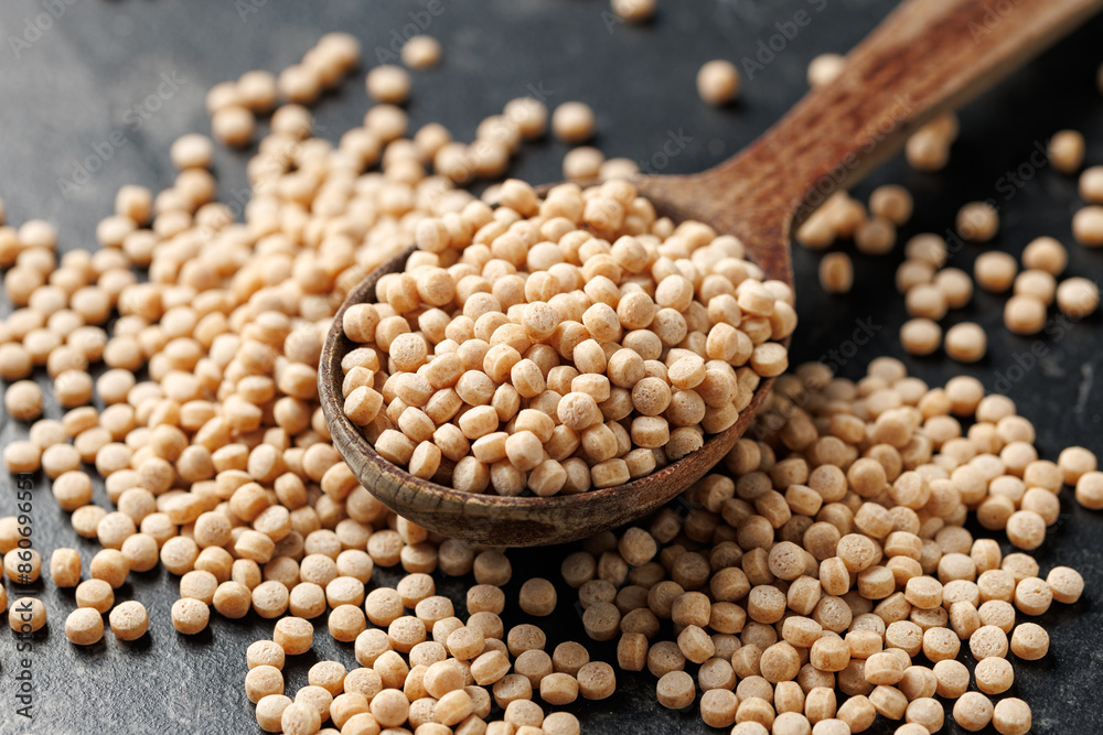 Fototapeta premium Giant or Pearl Wholewheat Couscous in a wooden spoon