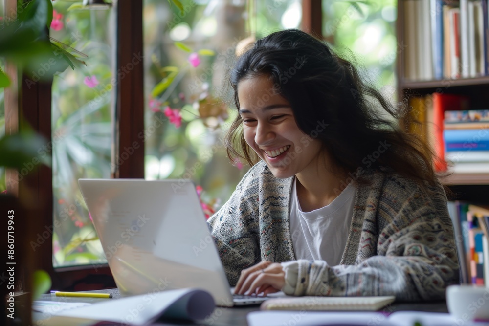 Joyful woman learning online at home, seated with laptop and notebook for studying and education Joyful woman learning online at home, seated with laptop and notebook for studying and education