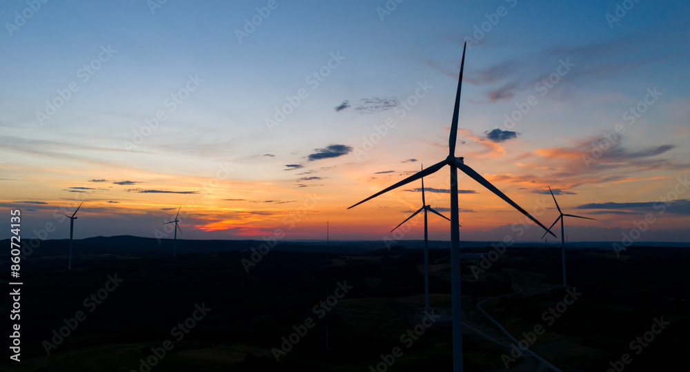 Obraz premium wind turbine in the countryside in the time of sunset background. Wind Turbines at Sunset. Aerial view of a wind farm at sunset.