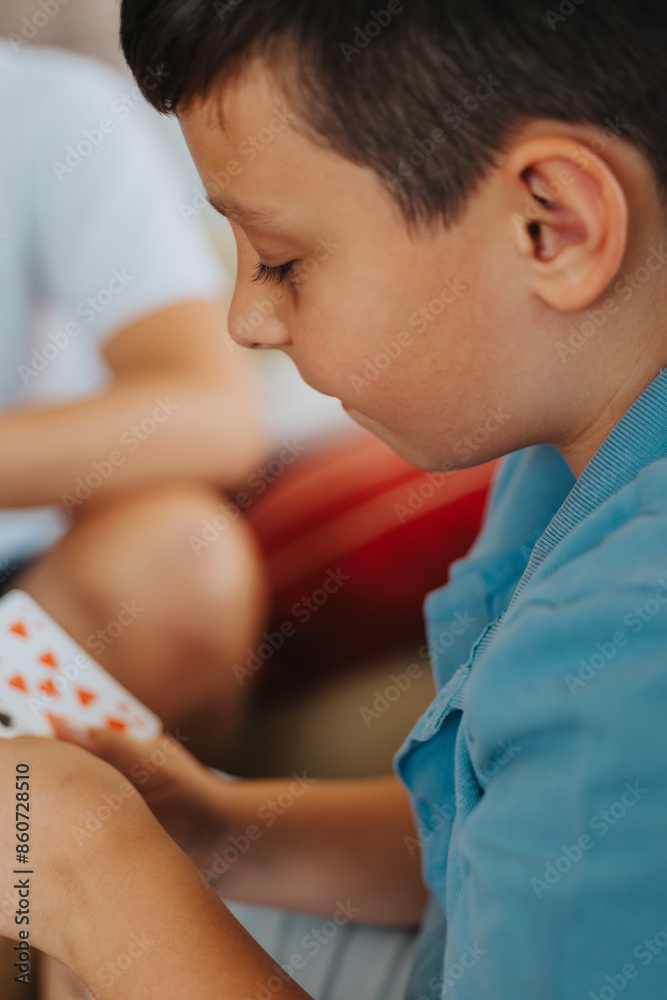 Close-up of a child deeply focused on a card game, illustrating family fun and bonding at home. Close-up of a child deeply focused on a card game, illustrating family fun and bonding at home.