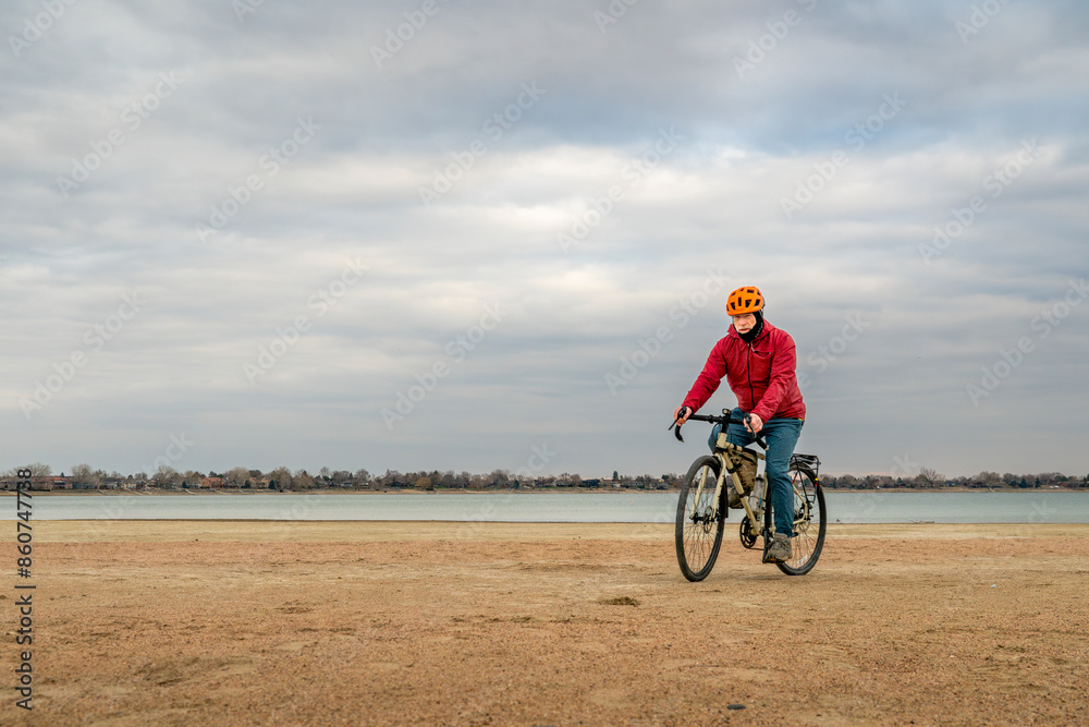 spring biking, touring or commuting - male cyclist with a bicycle on a lake beach, Boyd Lake State Park in northern Colorado