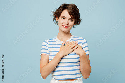 Canvastavla Young smiling happy grateful woman wearing striped t-shirt casual clothes put folded hands on heart look camera isolated on plain pastel light blue cyan background studio portrait