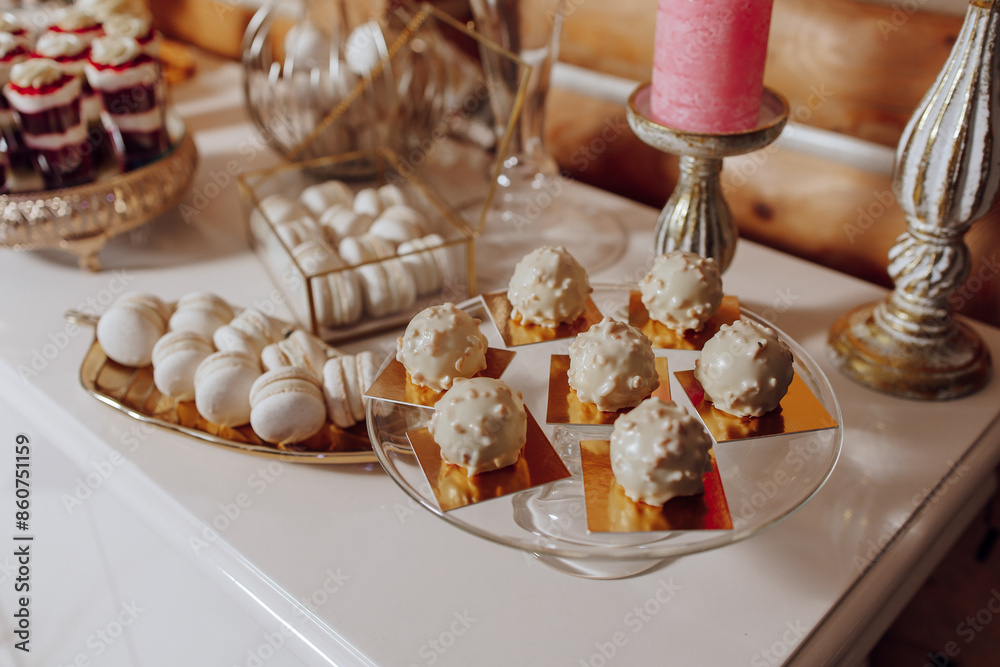 A table with a variety of desserts, including a tray of pastries and a cake. The desserts are arranged on a white table, and there are several different types of desserts, including cakes, pastries A table with a variety of desserts, including a tray of pastries and a cake. The desserts are arranged on a white table, and there are several different types of desserts, including cakes, pastries