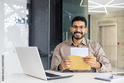 Happy man receiving a letter at his office desk with a laptop and notebook