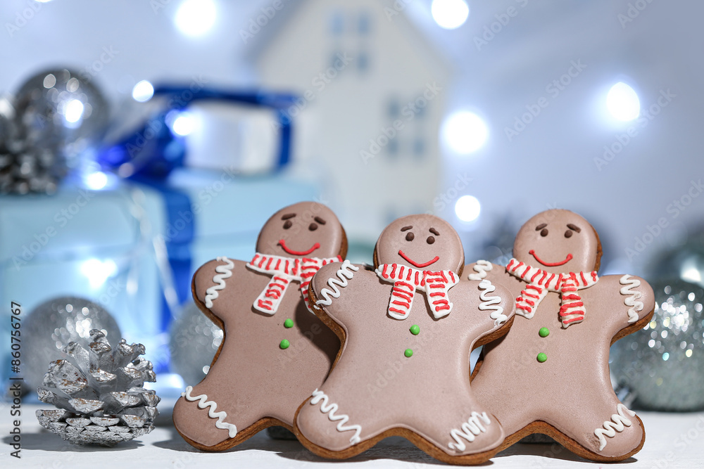 Fototapeta premium Christmas gingerbread cookies with silver pine cone and balls on table against blurred lights