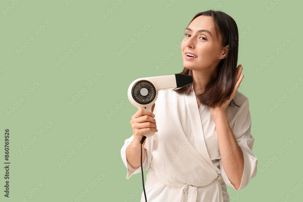 Fototapeta premium Beautiful young woman with hair dryer on green background