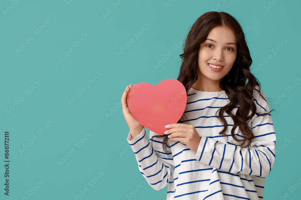 Beautiful young Asian woman with red paper heart on blue background. Valentine's Day celebration