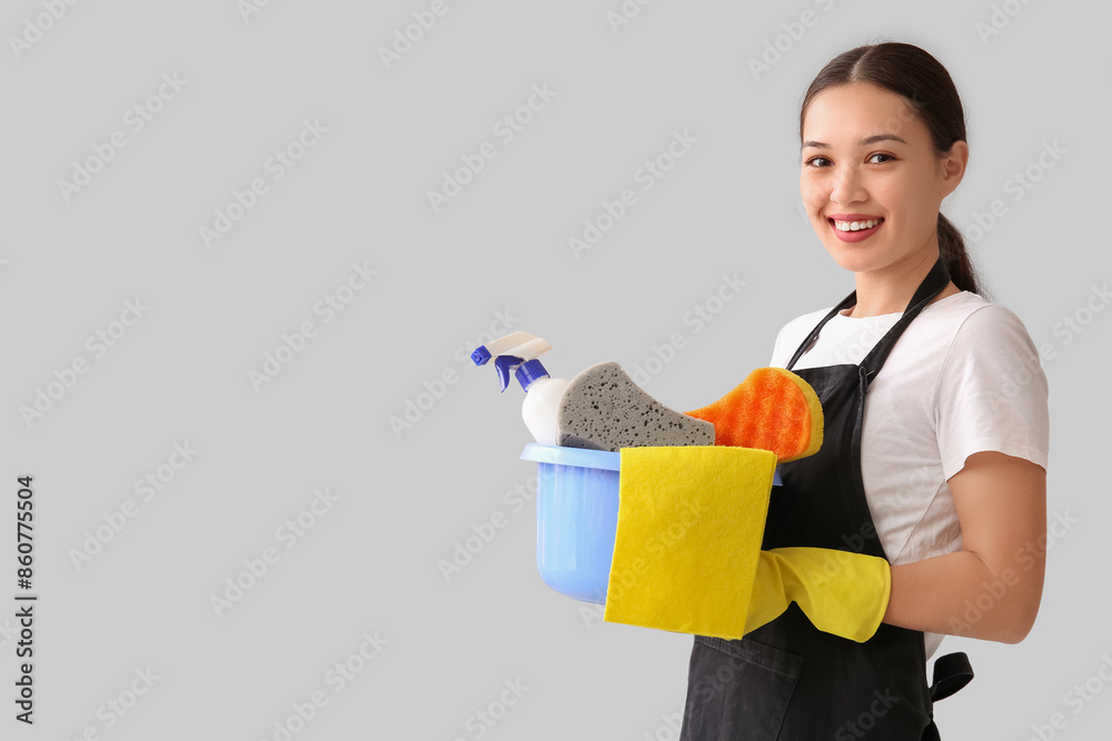 Young woman with cleaning supplies on light background Young woman with cleaning supplies on light background