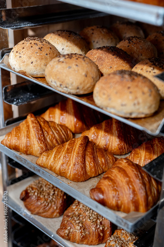 Close-up of freshly baked bread and croissants displayed on a rack in a bakery. Variety of baked goods photo