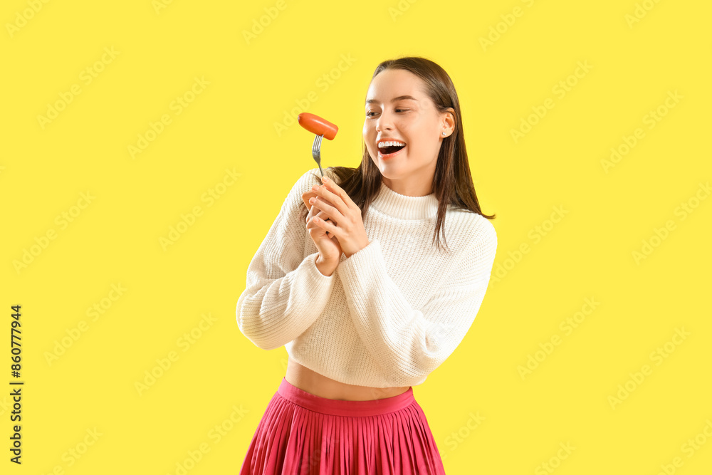 Young woman with tasty sausage on yellow background Young woman with tasty sausage on yellow background
