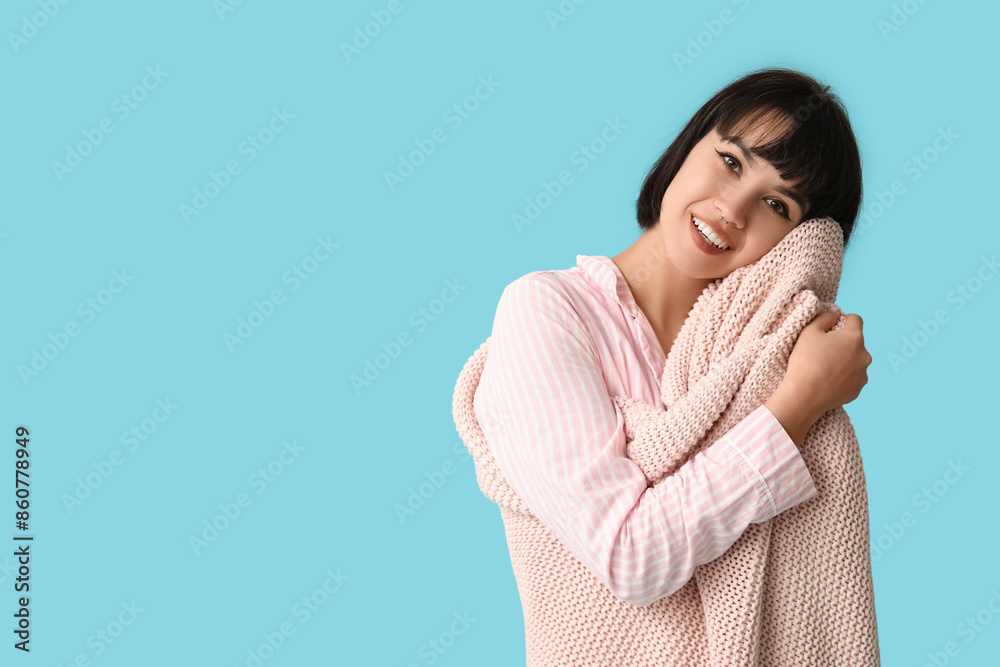 Beautiful young woman in pajamas with plaid on blue background Beautiful young woman in pajamas with plaid on blue background