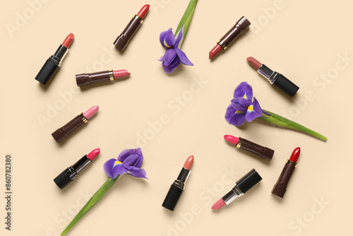 Frame made of lipsticks with flowers on beige background