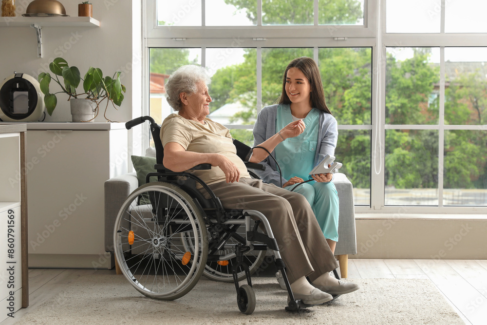 Senior woman in wheelchair with nurse measuring blood pressure at home Senior woman in wheelchair with nurse measuring blood pressure at home