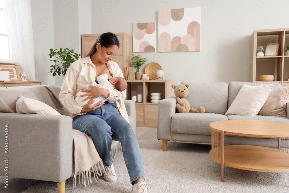 Young woman breastfeeding her baby on sofa at home Young woman breastfeeding her baby on sofa at home