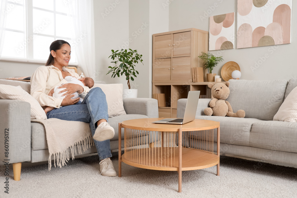 Young woman breastfeeding her baby on sofa at home Young woman breastfeeding her baby on sofa at home
