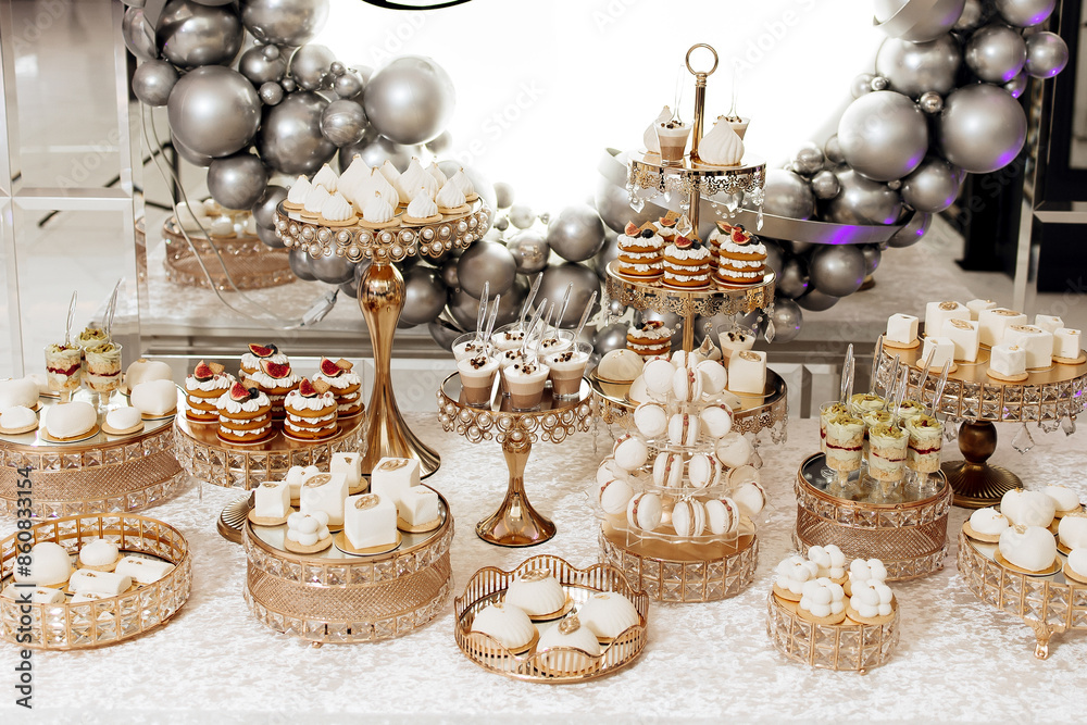 A table full of desserts and pastries with a silver and white theme A table full of desserts and pastries with a silver and white theme