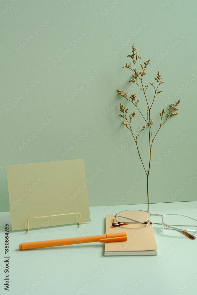 Workspace note, memo pad, eyeglasses, pen, dry flower on mint green desk background