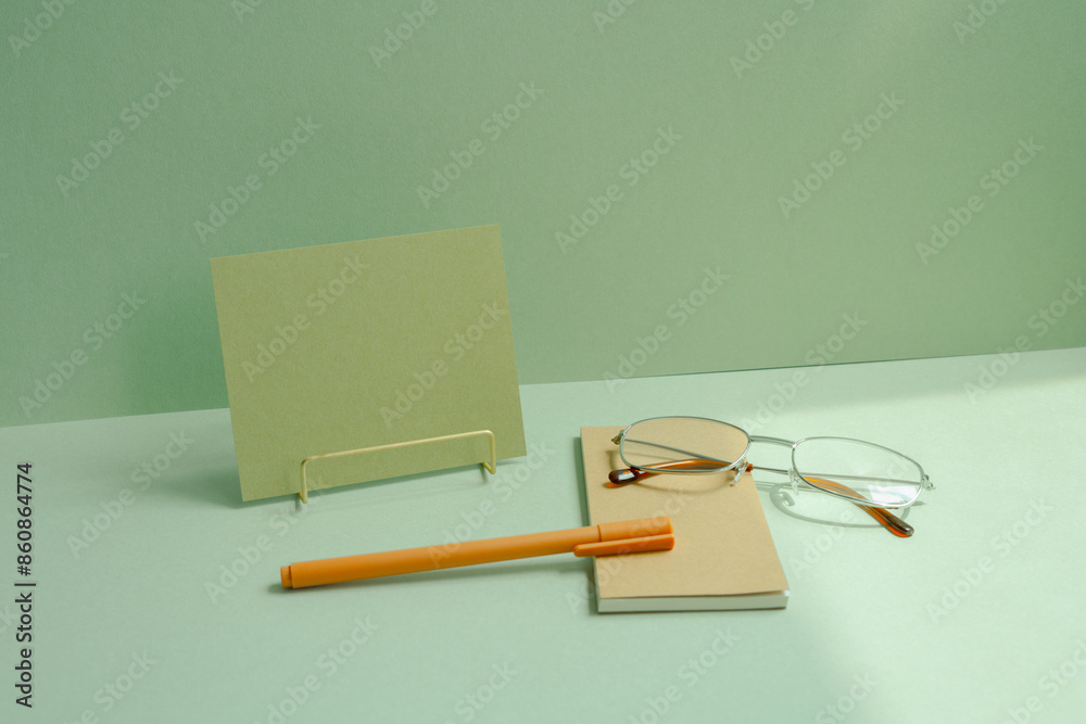 Workspace note, memo pad, eyeglasses, pen on mint green desk background