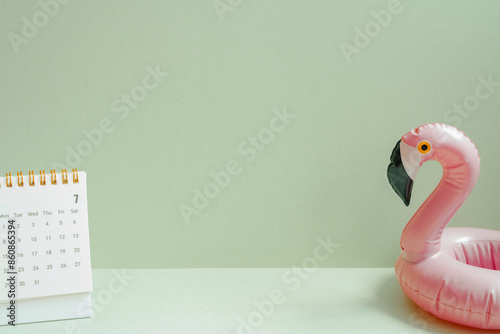 Obraz na płótnie Summer vacation planning concept. Pink flamingo bird shape swimming pool tube and calendar on mint green background w salonie