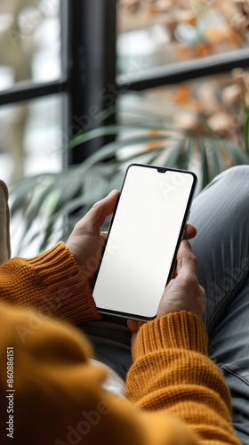 Mockup image of mobile smartphone with blank screen template, man sitting on sofa, hand holding and looking at mobile phone screen 