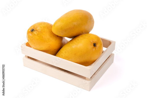 Three yellow Ataulfo mangos on a small wooden box isolated on white